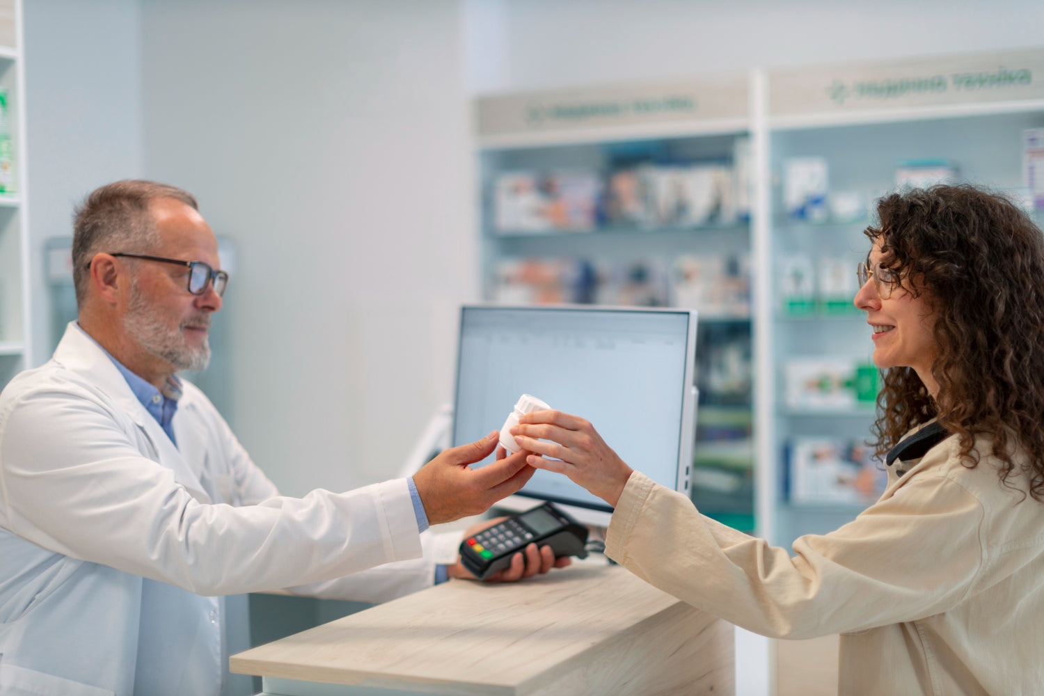A pharmacist handing a small white bottle of behind the counter to a supplements to a customer.
