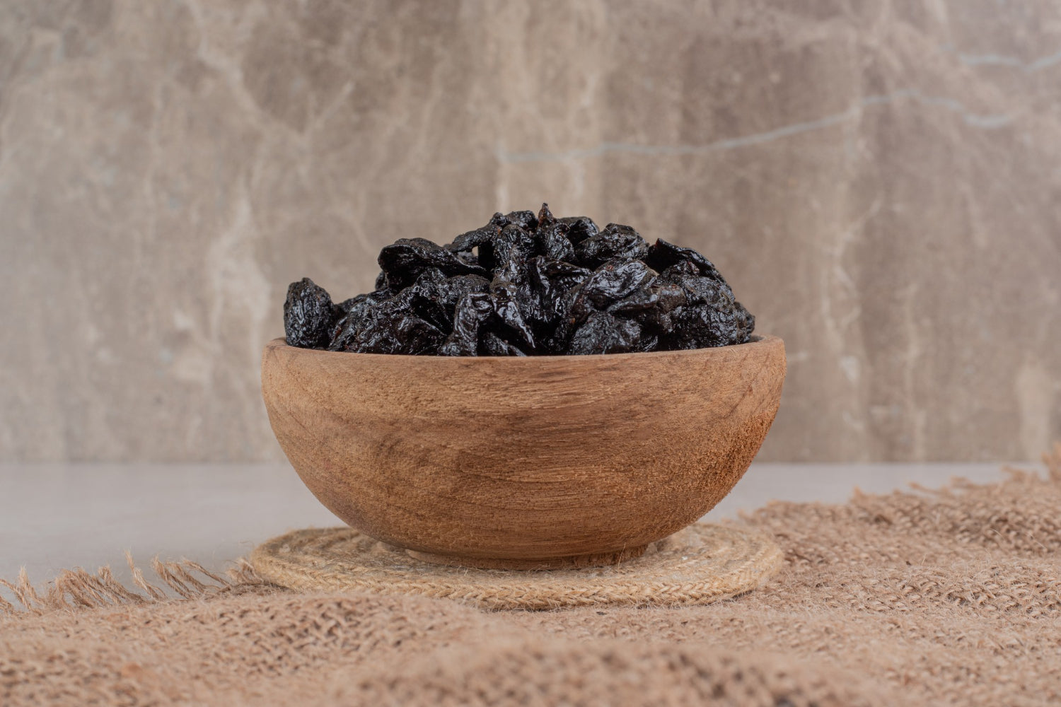 A wooden bowl full of pieces of shilajit on a table. The pieces are black and shiny.